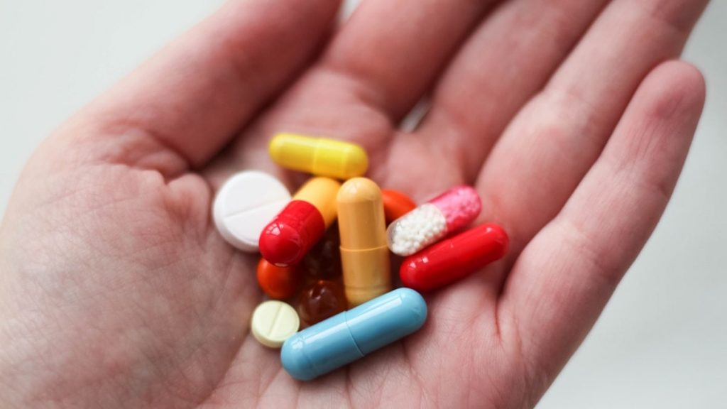 orange and white medication pill on persons hand