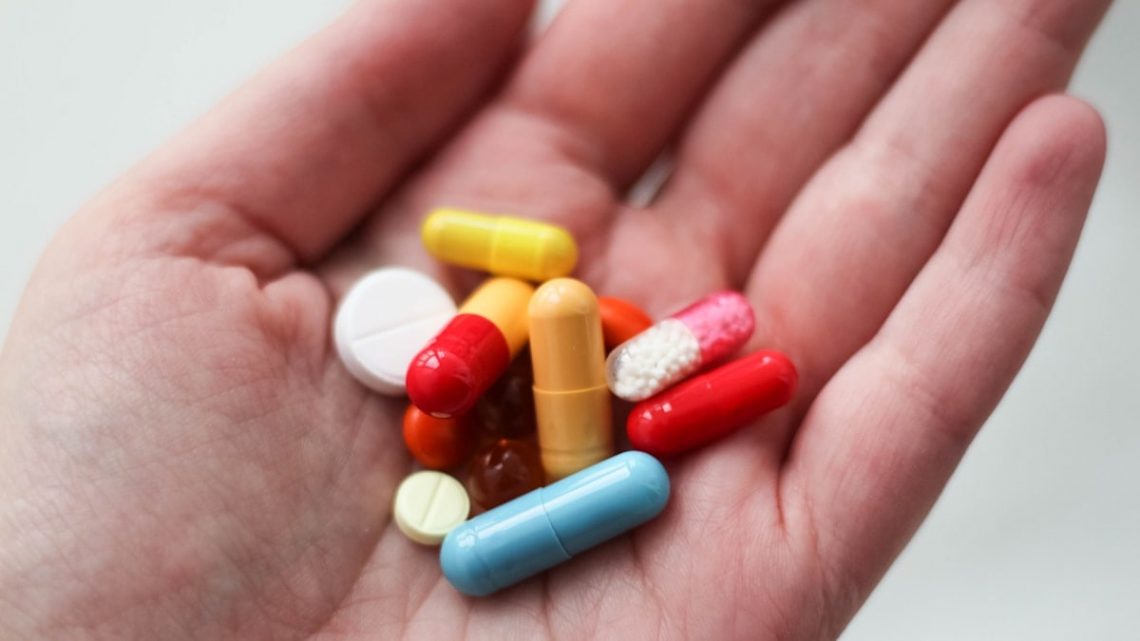 orange and white medication pill on persons hand