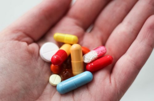 orange and white medication pill on persons hand